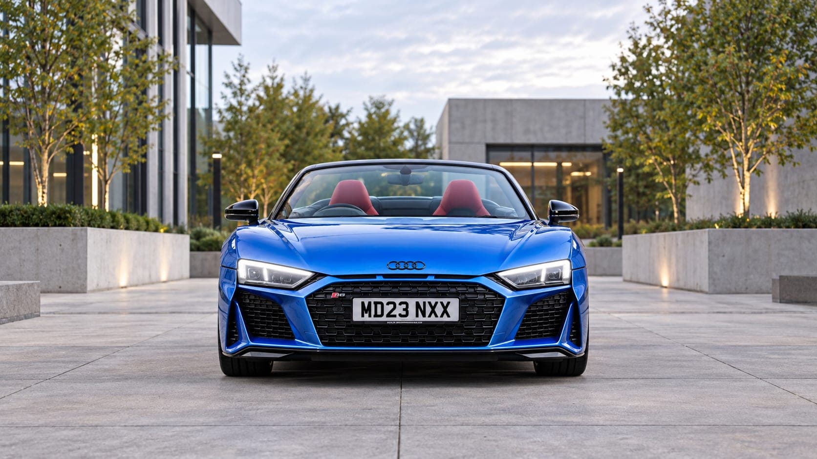 Blue Audi R8 Spyder V10 in a contemporary courtyard at dusk — self-drive supercar hire from CVS Car Hire